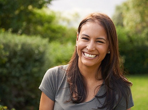 a smiling woman standing in a park