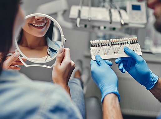 Woman looking at her smile after porcelain veneer restoration