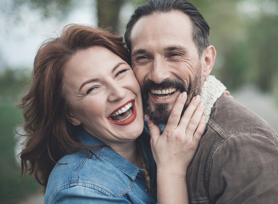 Man and woman with dentures smiling outdoors