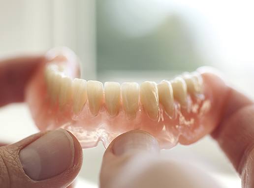 Hand holding full denture