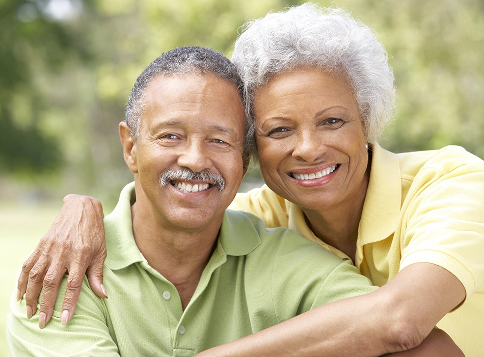 Man and woman smiling after full mouth reconstruction