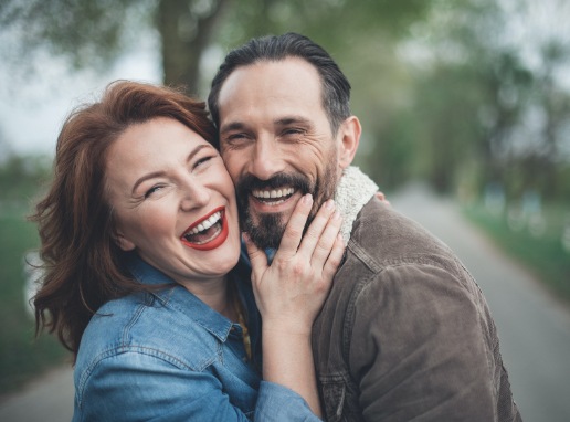 Man and woman laughing together after dental implant tooth replacement