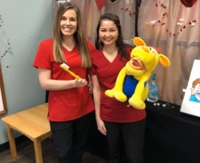 Dental team members with tooth brushing puppet