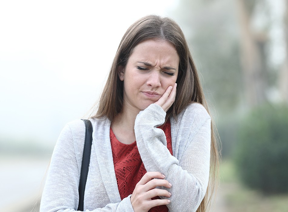 Woman in need of root canal therapy holding jaw in pain