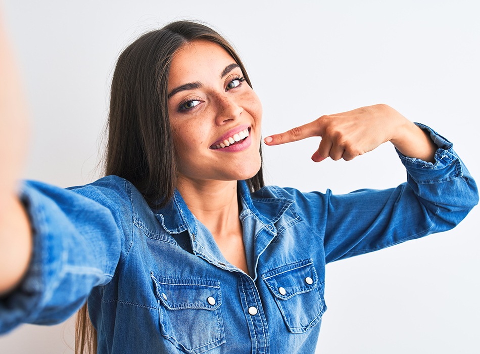 Woman pointing to her smile after makeover