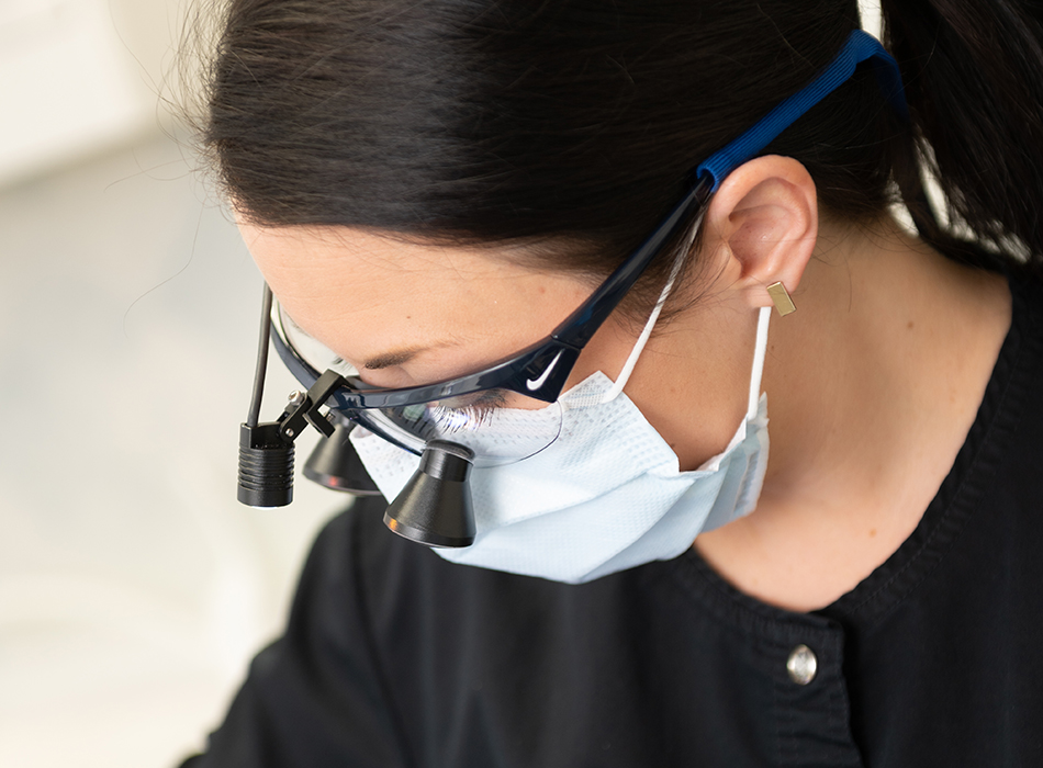 Dental team member using magnification loupes to treat dental patient