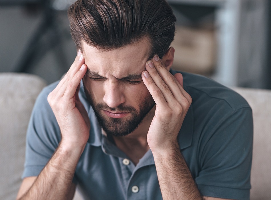 Man in need of T M J therapy holding his head