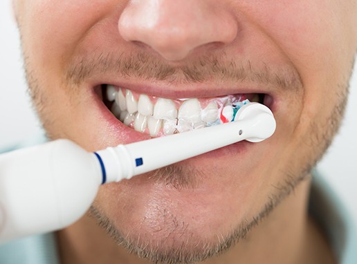 Patient brushing teeth to preserve teeth whitening results