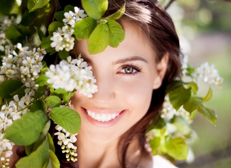 Beautiful woman smiling amid summer flowers.
