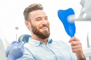 man smiling in a mirror while at the dentist