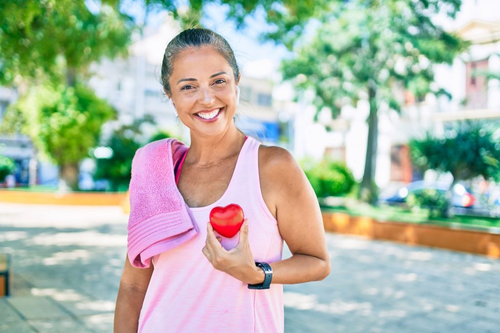 Woman in workout clothes holding heart-shaped prop