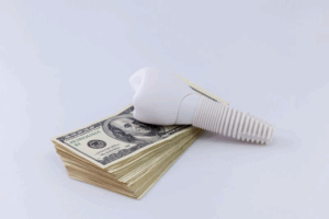 A dental implant laying on top of a stack of paper money