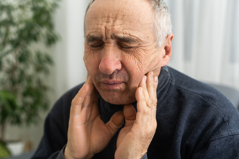 Patient rubbing cheeks due to ill-fitting dentures