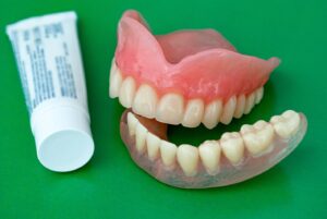 Set of dentures with tube of adhesive next to them.